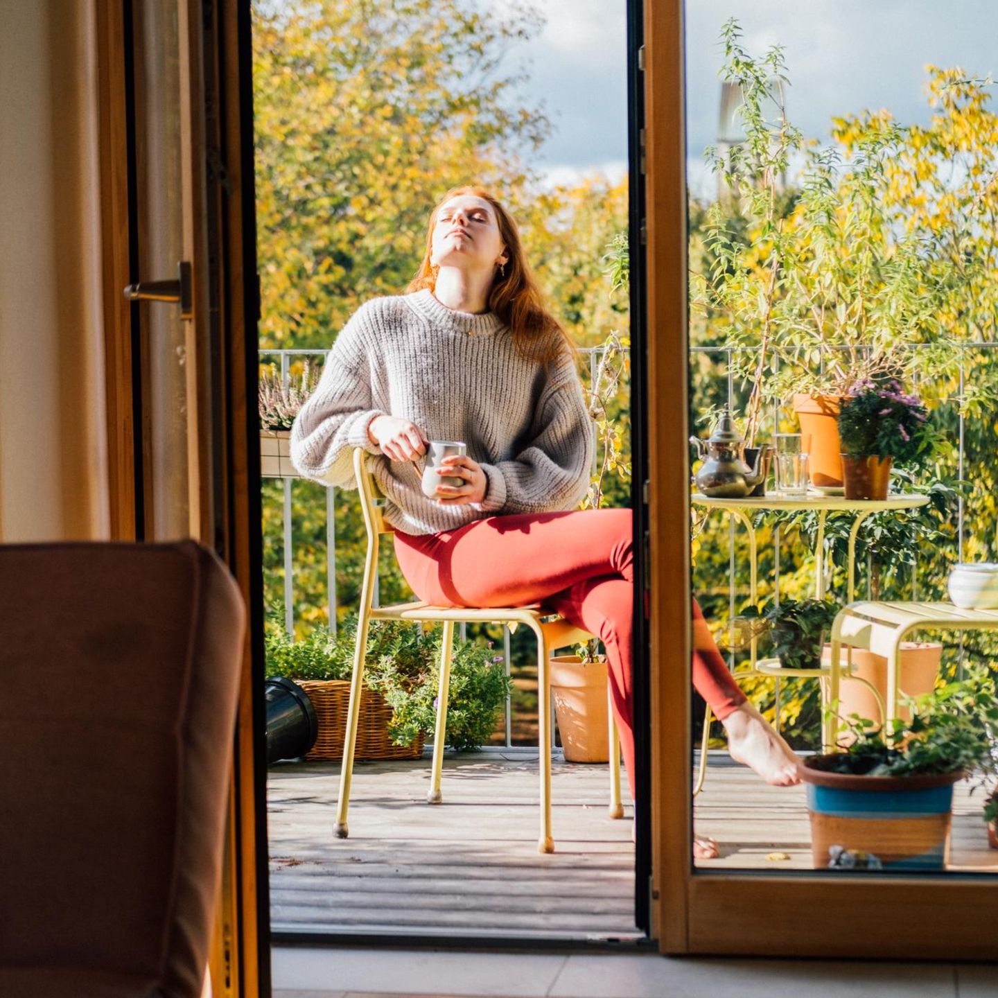 Eine junge Person genießt die Sonne auf dem Balkon