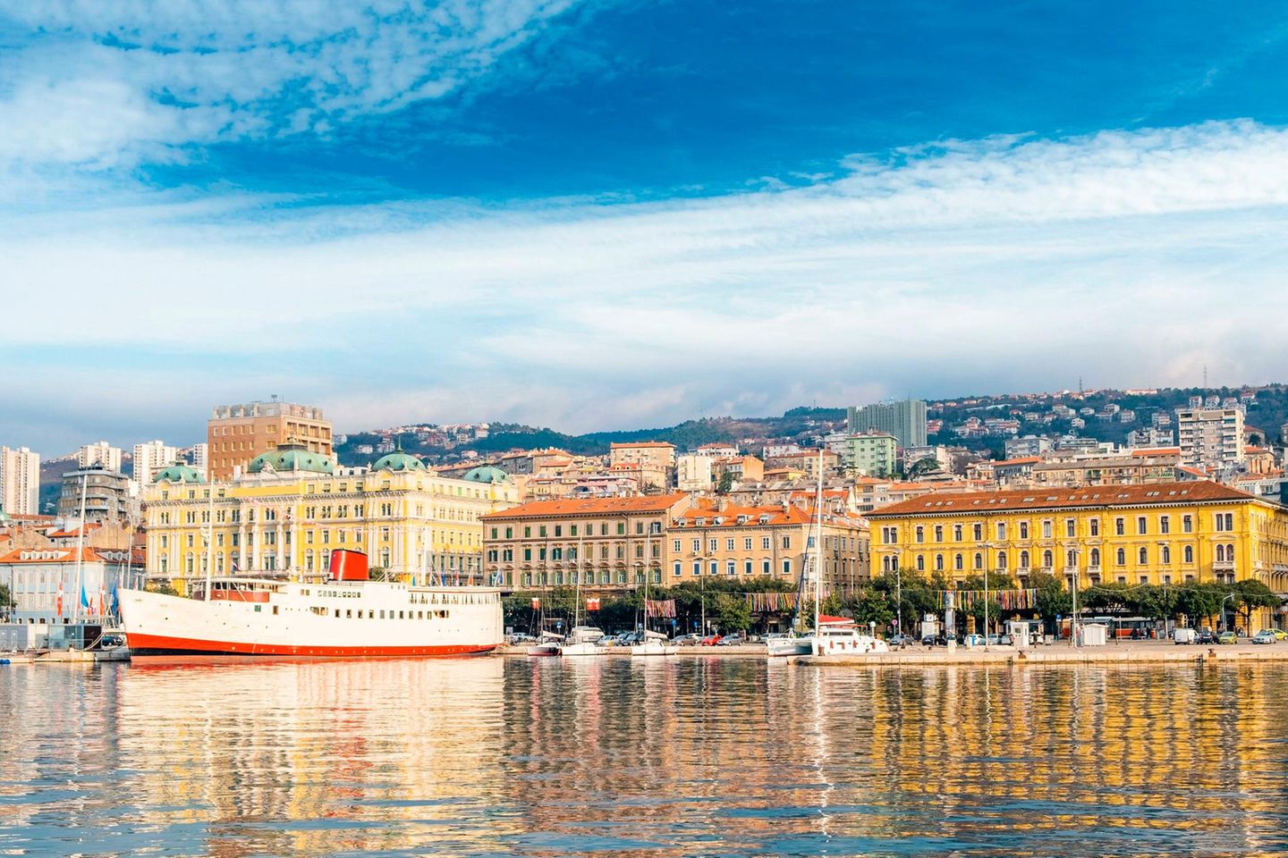 Schiff und Hafen von Rijeka vor bunten Hausfassaden