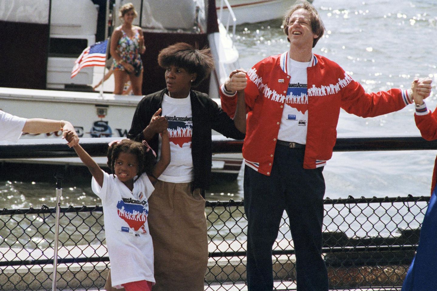 Ein Mädchen, ihre Mutter und ein Mann halten am Hafen von New York Händchen, 1986