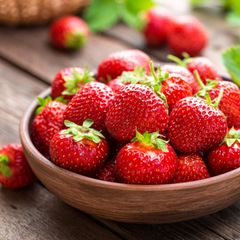 Frische Erdbeeren in Holzschale auf dem Gartentisch