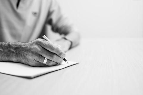 Nahaufnahme einer älteren Hand, die einen Brief schreibt