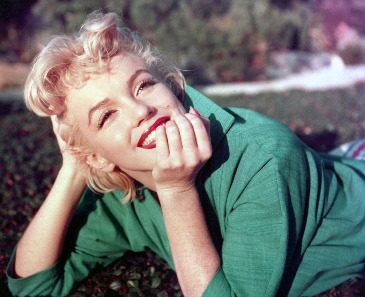 Marilyn strahlt in grünem Kleid - Kopf in die Hände gestützt