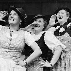 Drei Frauen im Dirndl rufen fröhlich etwas