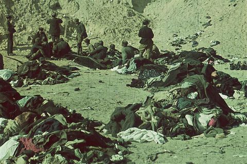 In einer Schlucht liegt Kleidung, die von Soldaten durchsucht wird